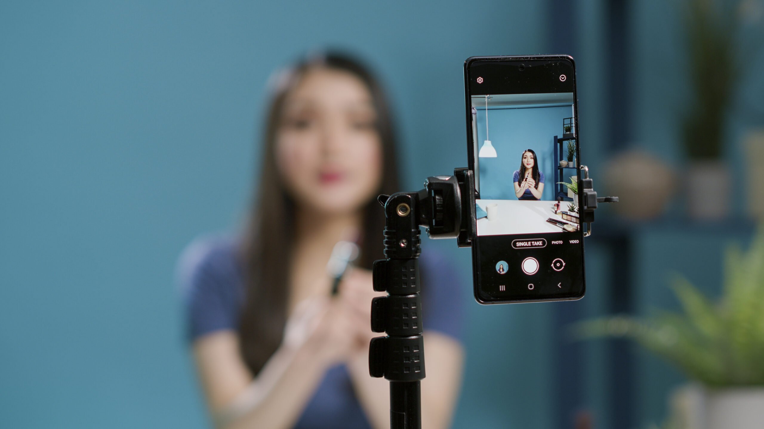 Content creator recording lifestyle vlog on filming camera, doing makeup tutorial for channel website. Female influencer broadcasting live video with beauty cosmetics products. Close up.
